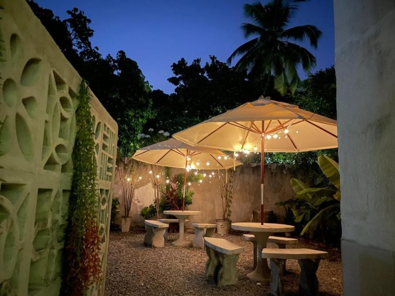 Terraza jardín nocturna con mesas de piedra y sombrillas iluminadas en Refúgio Pousada Fortaleza