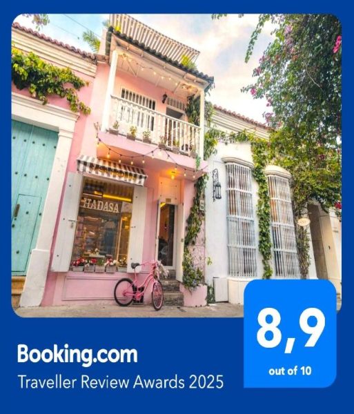 Fachada colonial rosa de Casa Hadasa en Cartagena con balcón, plantas y bicicleta rosa, premiada por Booking.com
