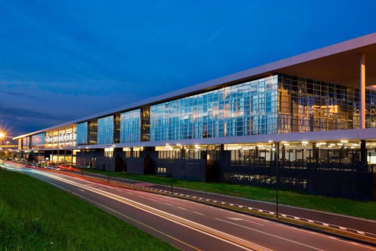 Fachada exterior iluminada del Sheraton Milan Malpensa Airport Hotel & Conference Centre al anochecer