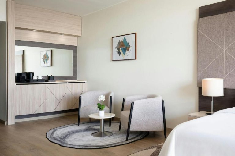 Habitación doble con zona de estar, sillas y minibar del Sheraton Milan Malpensa Airport Hotel