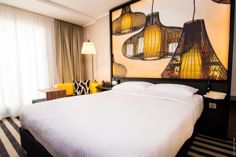 Habitación doble del Simon Hotel con gran cabecero decorativo de lámparas y cama king size en blanco