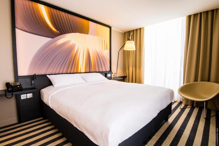 Habitación doble con cama matrimonial y cabecero decorativo en el Simon Hotel