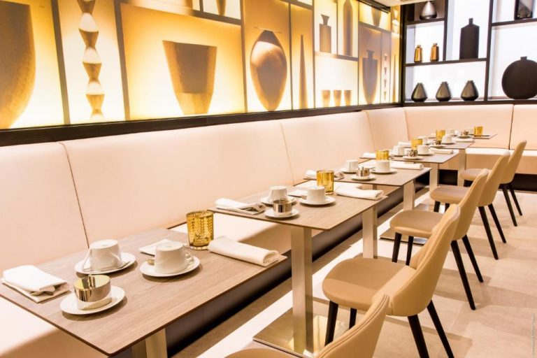 Restaurante elegante del Simon Hotel con mesas preparadas para el desayuno y decoración dorada en tonos cálidos