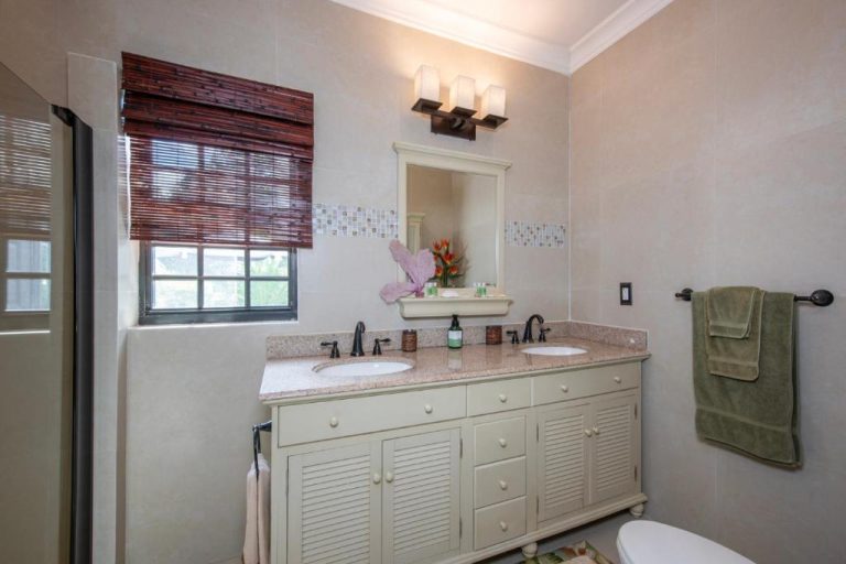 Baño doble con encimera de granito, armario blanco y toallas verdes en The Pilot House