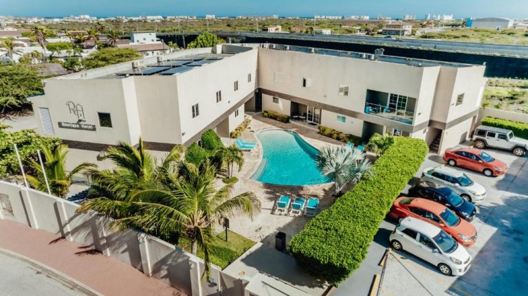 Vista aérea de la piscina exterior y aparcamiento del Hotel RH Boutique Aruba con palmeras