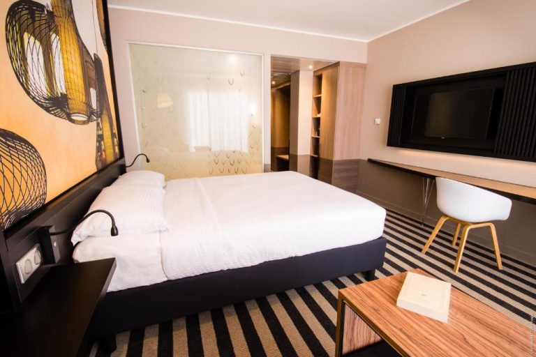 Habitación doble moderna con cama matrimonial, televisión y escritorio en el Simon Hotel