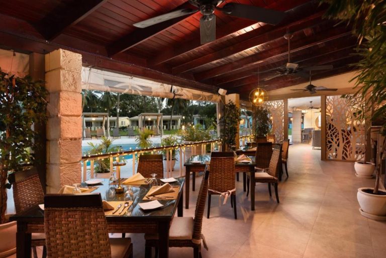 Terraza restaurante con mesas elegantes y vistas a la piscina del All Seasons Resort