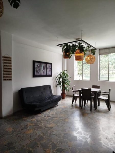 Sala de estar y comedor con sofá, mesa y plantas en el Hotel Bayadera Real