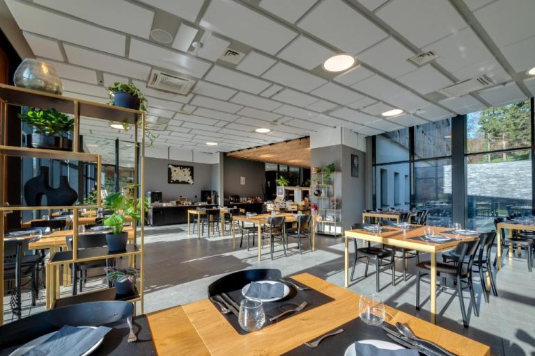 Restaurante moderno con mesas de madera y sillas negras en el Lyra Hotel Plitvice