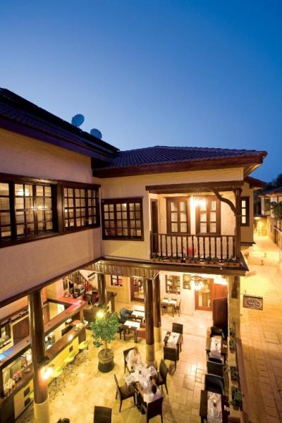 Terraza exterior con restaurante iluminado al atardecer en el Cicerone Lodge Hotel