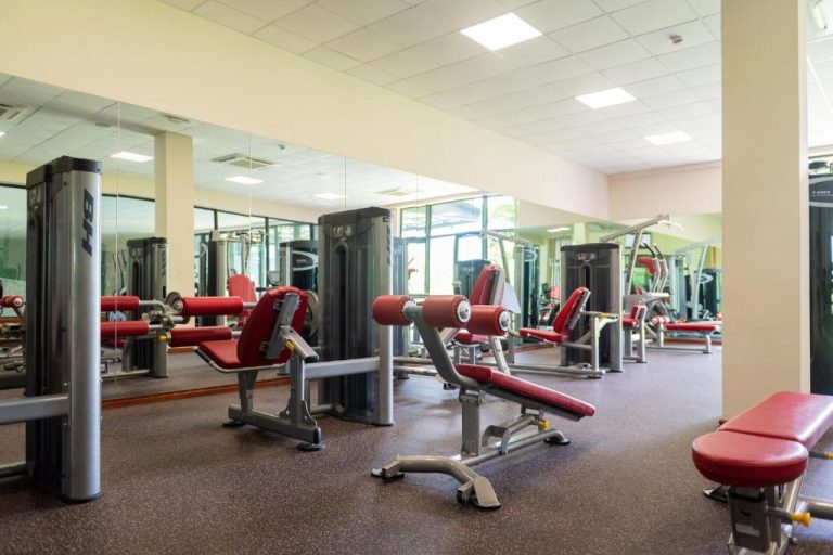 Gimnasio completamente equipado con máquinas de musculación y espejos en Royal Green Wellness Resort