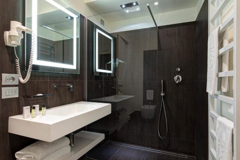 Baño moderno con ducha de lluvia y espejo iluminado del Hotel Tiferno