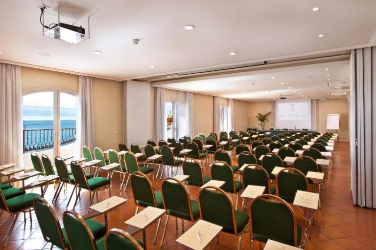 Sala de conferencias con sillas verdes y vistas al mar en el Grand Hotel Baia Verde