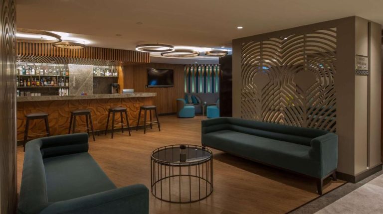 Bar y zona lounge del DoubleTree by Hilton Istanbul Sirkeci con sofás verdes y barra de cócteles