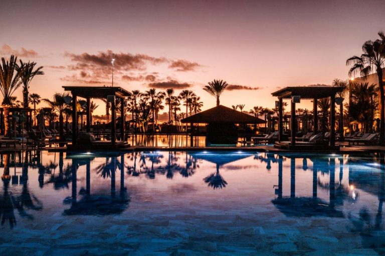 Piscina exterior iluminada al atardecer con palmeras en el Hotel Riu Palace Tikida Agadir All Inclusive