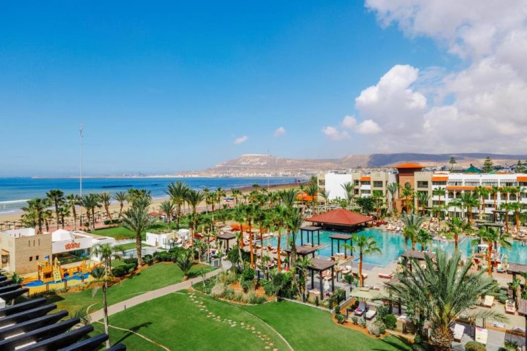 Piscina exterior rodeada de palmeras con vistas a la playa en Hotel Riu Palace Tikida Agadir All Inclusive
