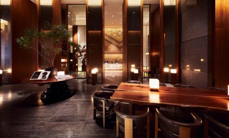 Lujoso lobby del Andaz Tokyo Hyatt con mesa de madera natural, árbol interior y recepción iluminada