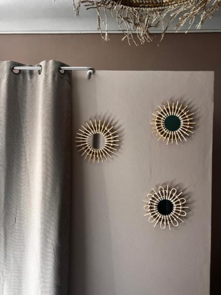 Decoración de pared con espejos redondos de ratán estilo boho en el Hotel Fleur des Alpes