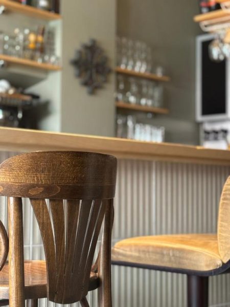 Bar con elegantes taburetes de madera tallada y estantes con copas en el Hôtel Fleur des Alpes
