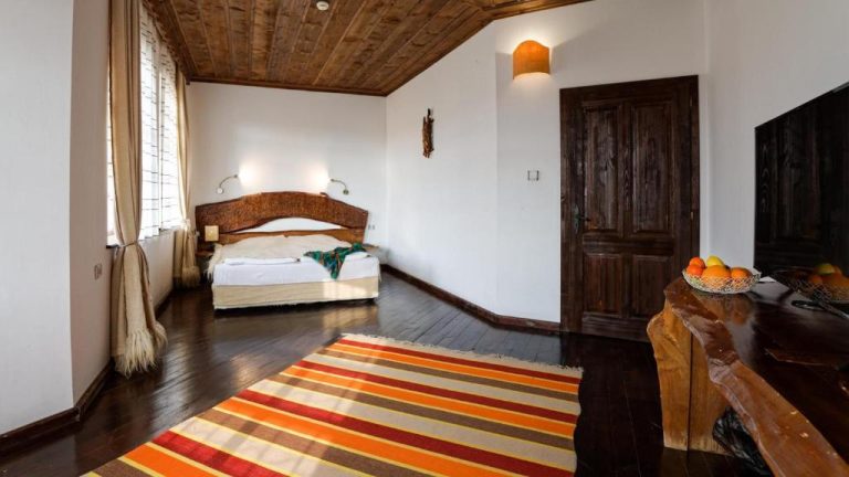 Habitación doble con decoración rústica de madera y alfombra de colores en Wine & Spa Complex Starosel