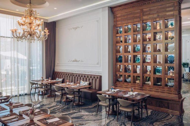 Restaurante elegante del Iberostar Waves Slavija con vitrina de madera, araña de cristal y mesas preparadas