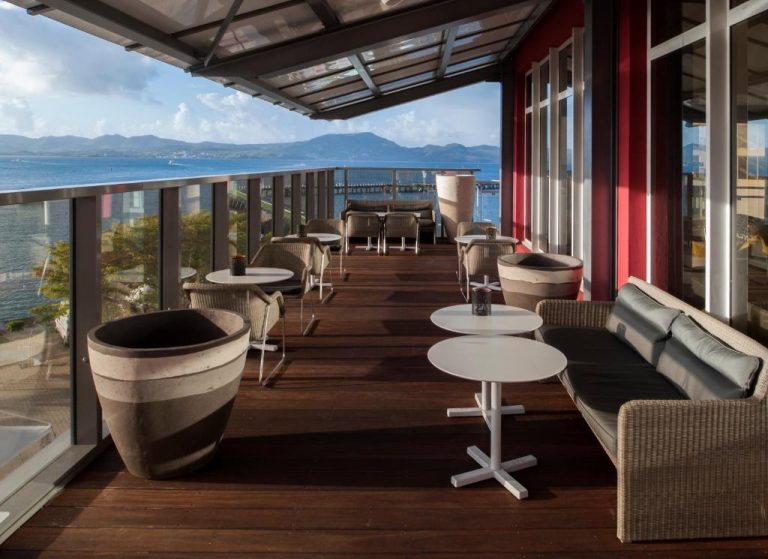 Terraza exterior con mesas y sofás del Simon Hotel con vistas panorámicas al mar y montañas