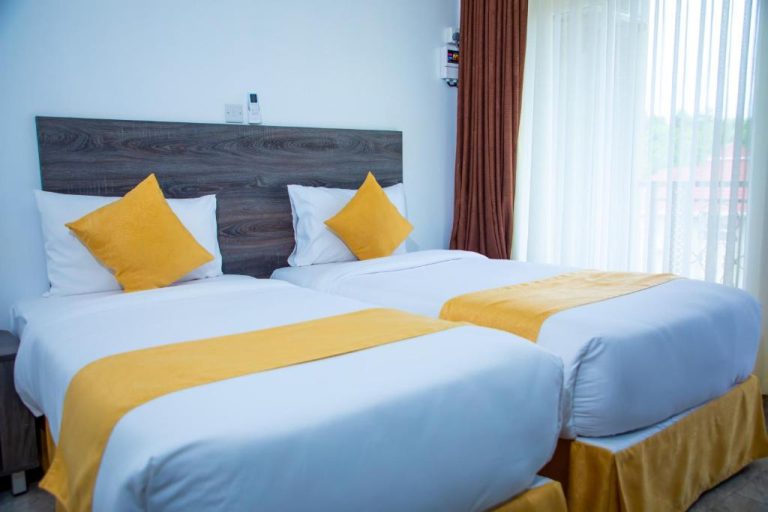 Habitación doble con dos camas y decoración en amarillo y blanco en Kisimani Eco Resort & Spa
