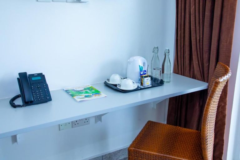 Escritorio de habitación con tetera, tazas, teléfono y botellas de agua en Kisimani Eco Resort & Spa