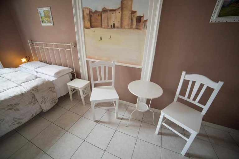Habitación doble del Hotel Biscari con cama, sillas y mesa blancas y cuadro decorativo en la pared