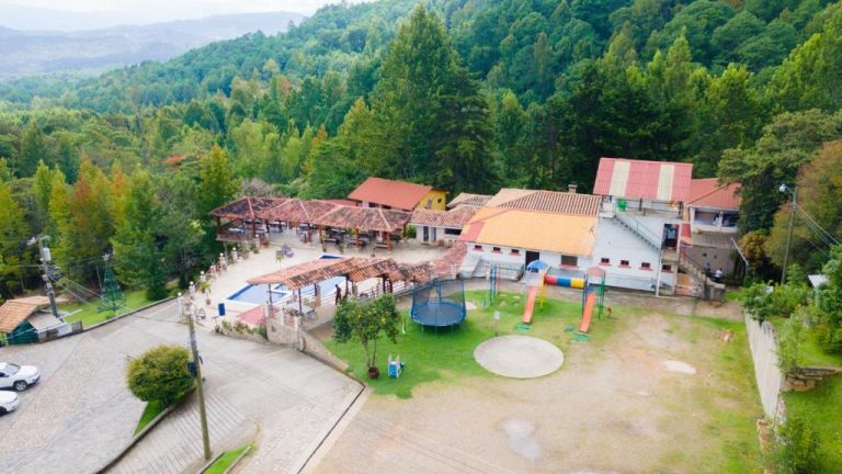 Vista aérea de las instalaciones del Hotel y Cabañas ROS con piscina, área de juegos y entorno boscoso