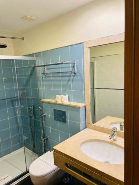 Baño moderno con ducha acristalada y azulejos azules en el Beramar Hotel