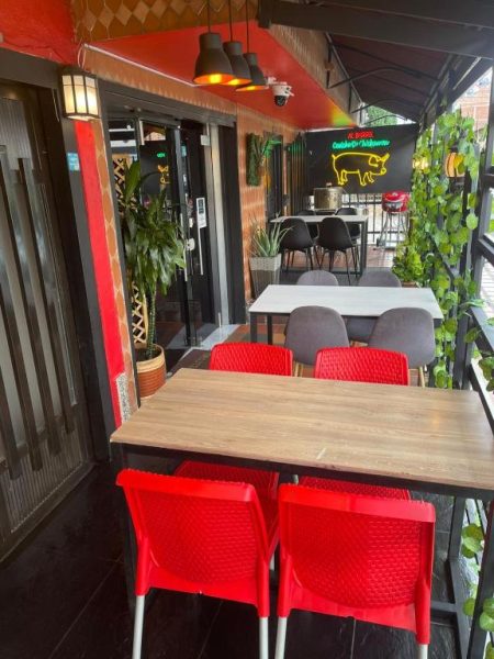 Terraza restaurante con sillas rojas y neón decorativo de cerdo en Hotel San Pablo Boutique H9