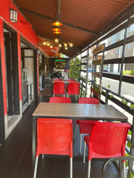 Terraza restaurante con mesas de madera y sillas rojas en Hotel Boutique San Pablo H10