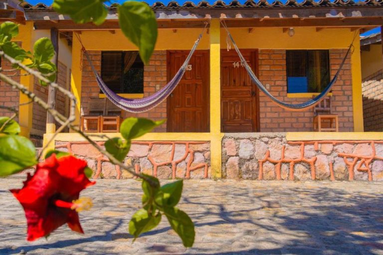 Cabañas con hamacas y terraza de piedra en Hotel Villas del Valle con flor de hibisco roja