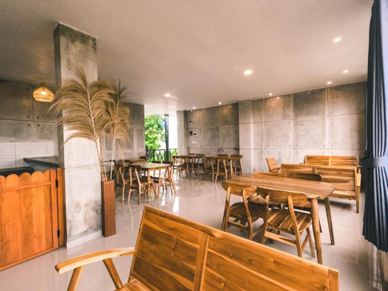 Salón comedor con mesas y sillas de madera natural en Zavana Rooms & Restaurant, estilo industrial