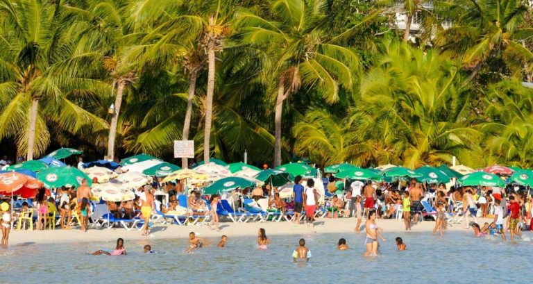 Playa del Hotel Hannabi con turistas disfrutando del mar, sombrillas de colores y palmeras tropicales