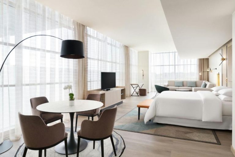Suite junior con zona de comedor, cama king y sala de estar en Sheraton Milan Malpensa Airport Hotel