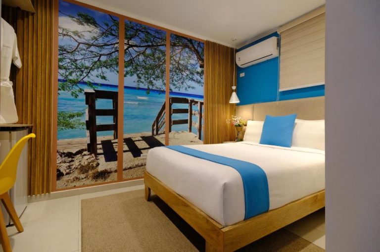 Habitación doble con mural de playa tropical y decoración en azul del Victoria City Hotel