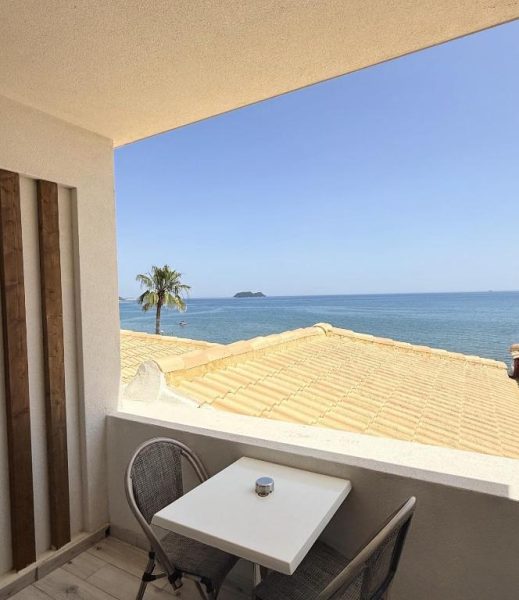 Balcón con mesa y sillas del Crystal Beach Hotel con vistas al mar y palmera