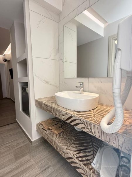 Baño moderno con lavabo sobre encimera decorativa y paredes de mármol en Crystal Beach Hotel