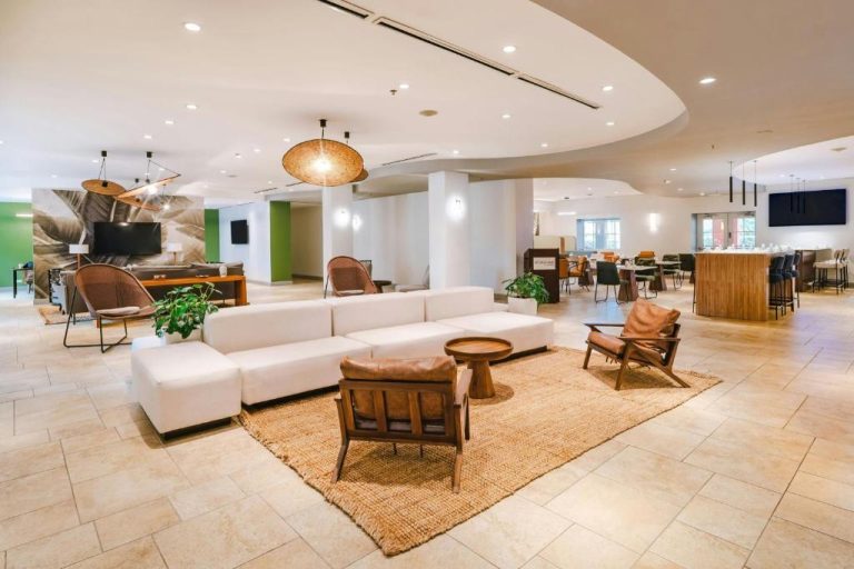 Amplio lobby lounge con sofás blancos y sillas de madera del Courtyard by Marriott Bridgetown Barbados