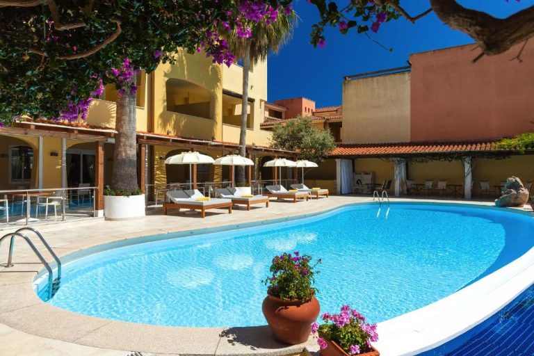 Piscina exterior con tumbonas y sombrillas del Hotel Villa Margherita rodeada de jardín mediterráneo