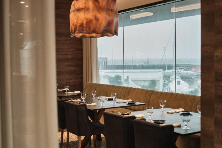 Restaurante del Octant Ponta Delgada con mesas elegantes y vistas panorámicas al puerto deportivo