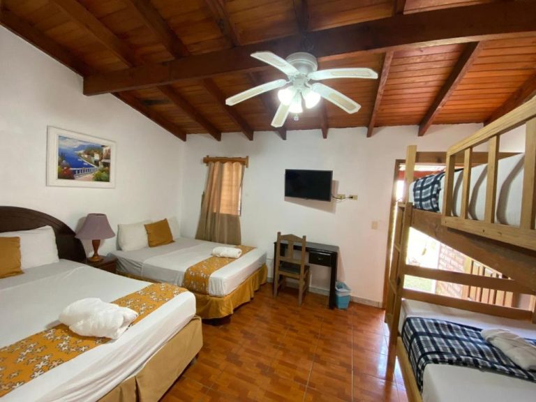 Habitación cuádruple con camas y literas de madera en Hotel Villas del Valle con techo de vigas