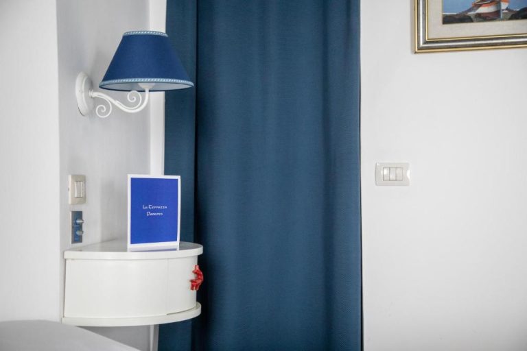 Detalle de habitación con lámpara azul y mesita de noche blanca en Hotel La Terrazza Panarea