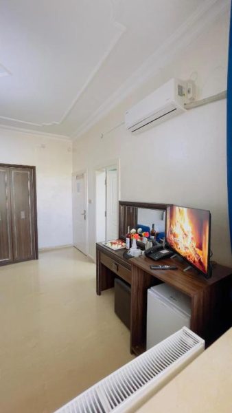Habitación del Turabdin Hotel con escritorio de madera, televisión y aire acondicionado en la pared