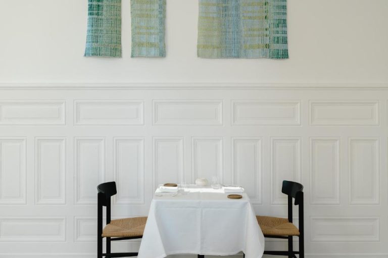 Mesa elegante para dos en el restaurante del hotel Les Hauts de Sancerre con decoración minimalista en blanco