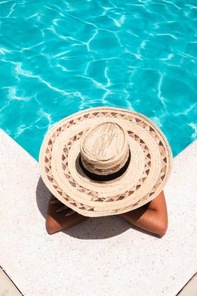 Mujer relajándose junto a la piscina turquesa del Landhuis Daniel Plantation House en Curaçao