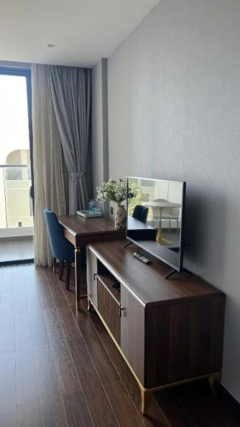 Habitación con escritorio de madera, televisor y silla azul en Hanna Seaview Stella The Arena Resort