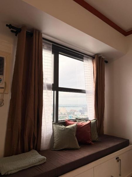 Asiento junto a la ventana con cojines y vistas panorámicas de la ciudad en Skyline Luxe Cebu
